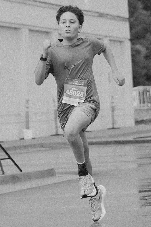 Nour mid-stride in a marathon, race bib 45028 pinned to his shirt