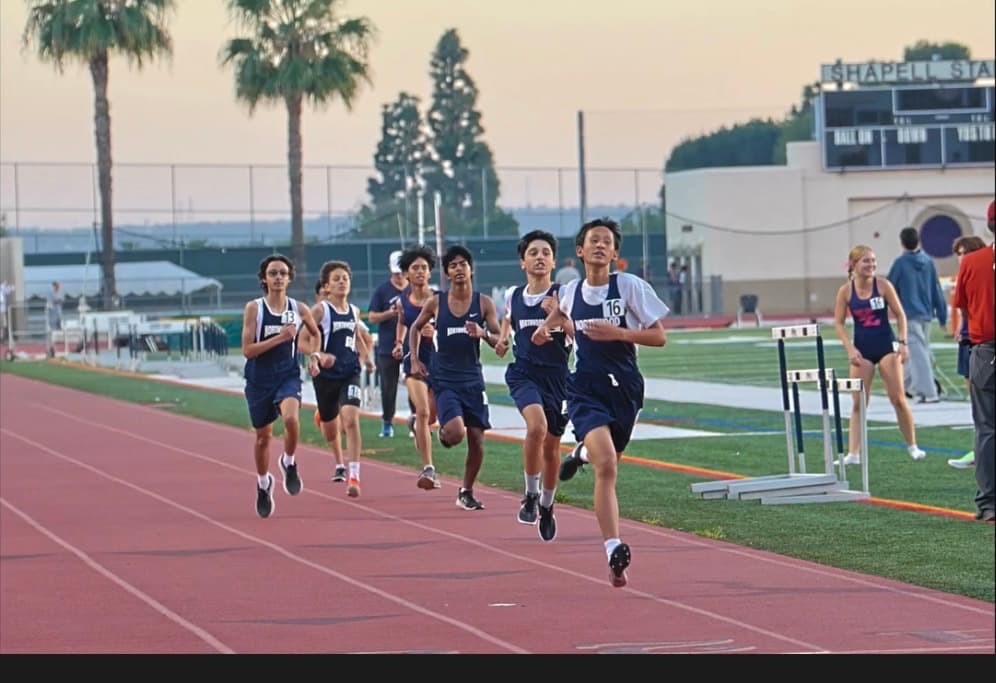 Northwood runners racing toward the camera on a red track