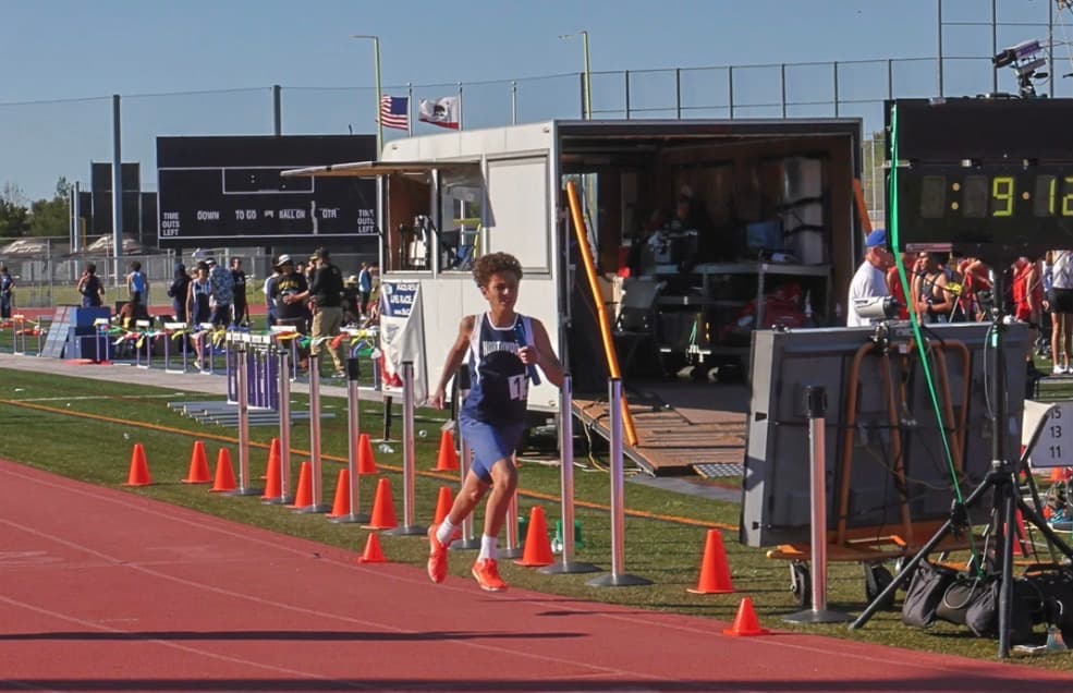 Nour in a Northwood singlet running a relay with a blue baton
